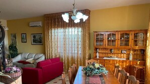 Ein Essbereich mit Holztisch und Stühlen, einem roten Sofa und einer Vitrine.