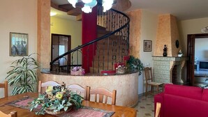 Ein Essbereich mit einem Holztisch, gedeckt für vier Personen, umgeben von Stühlen. Im Hintergrund ist eine rote Couch zu sehen.