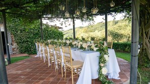 Un espace de restauration en plein air, avec des tables dressées pour le repas, entouré de verdure et avec une chaîne de montagnes en toile de fond.