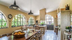 Una cocina amplia con ventanas grandes, muebles de madera y diversos electrodomésticos.