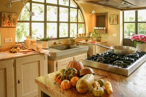 A kitchen with a gas stove, a sink, and a window with a view of greenery. - Villa Fratini - Six Bedroom Villa, Sleeps 12 (Terranuova Bracciolini)