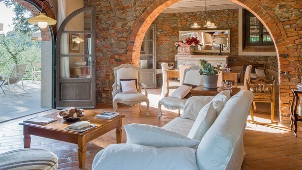 Un salón acogedor con una pared de piedra, un sofá blanco y una mesa de centro de madera.