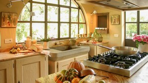 Una cocina con estufa a gas, un lavamanos y una ventana con vistas a la vegetación.