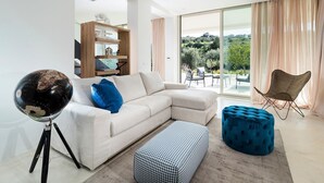 A modern living room with a white sectional sofa, a globe on a tripod stand, a patterned ottoman, and a blue tufted ottoman.