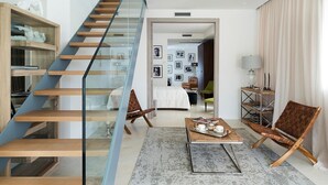 A modern living room with a glass staircase, a coffee table, and a sofa.