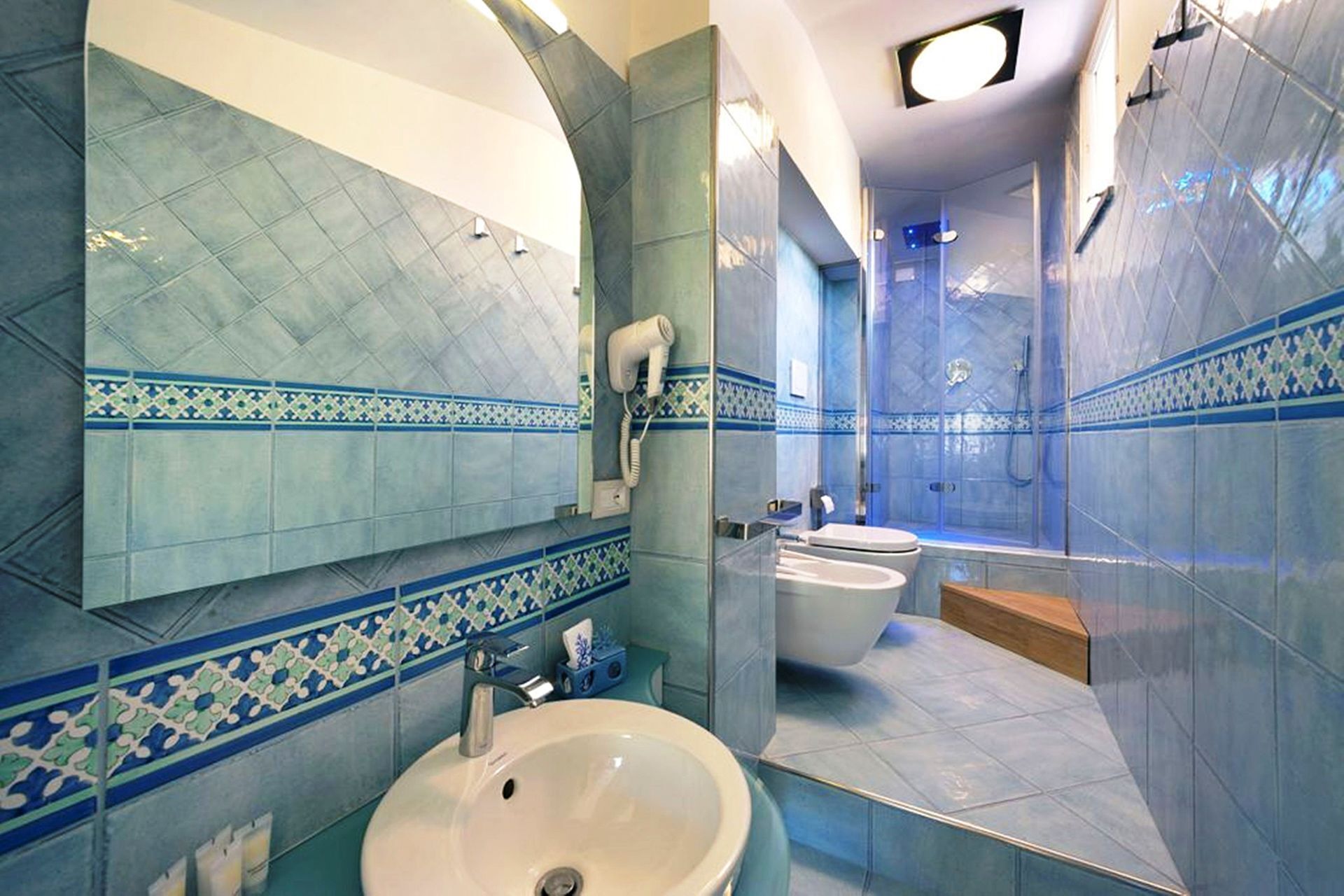 A bathroom with a sink, mirror, and shower area.