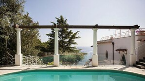 Ein Pool mit Pergola, umgeben von Grün und mit Blick auf eine schöne Landschaft.