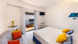 Ein Hotelzimmer mit Bett, einer Couch, einem Fernseher und Meerblick.