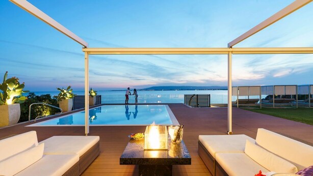 A poolside area with a view of the sea, outdoor seating, and a table with a fire feature. - Villa Incanto - Four Bedroom Villa, Sleeps 8 (Plemmirio)