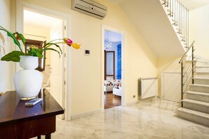 A hallway with a marble floor, a white vase with flowers, a remote control, and a staircase with a metal railing. - Villa Erice - Three Bedroom Villa, Sleeps 6 (Custonaci)