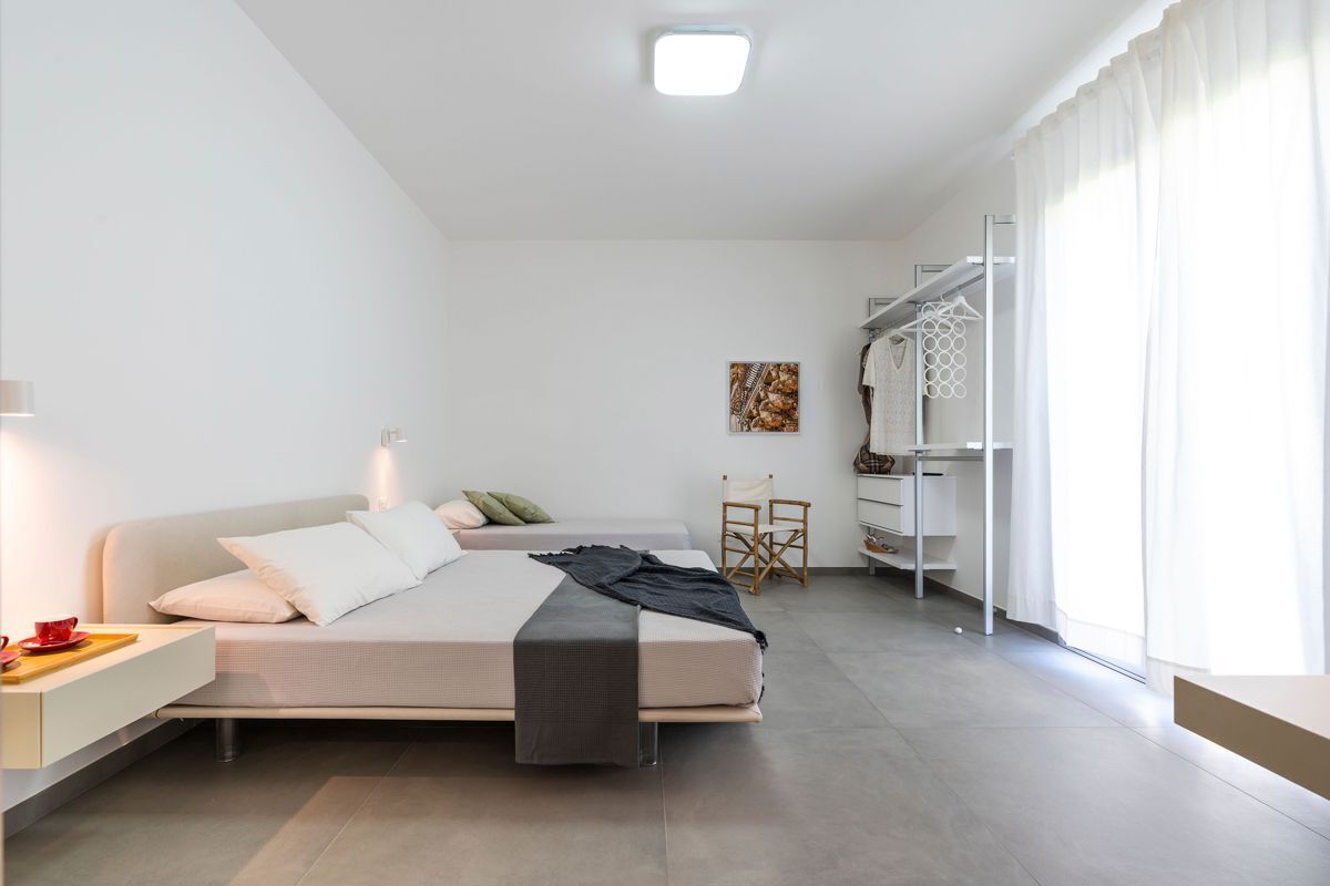 A modern bedroom with a bed, bedside table, chair, and a wardrobe.