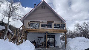 A two-story building with a balcony, wooden stairs, and a snow-covered ground.