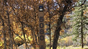 A wooden signpost with the number 5080 A.C. in a natural setting with trees and gravel.