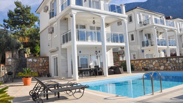A two-story building with balconies, a swimming pool, and outdoor furniture. - Villa Gunes - Three Bedroom Villa, Sleeps 6 (Ölüdeniz Belediyesi)