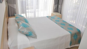 A neatly made bed with a white and blue patterned bedspread, a wooden headboard, and a bedside table. - Villa Gunes - Three Bedroom Villa, Sleeps 6 (Ölüdeniz Belediyesi)