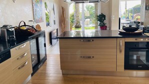 A modern kitchen with a large island, built-in appliances, and a view of the outdoor garden. - Villa 6pers splendid sea view and magnificent landscaped park in the peace with swimming pool (Grosseto-Prugna)