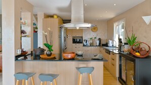 A modern kitchen with a central island, bar stools, and a variety of kitchen appliances and decor. - Villa 6pers splendid sea view and magnificent landscaped park in the peace with swimming pool (Grosseto-Prugna)