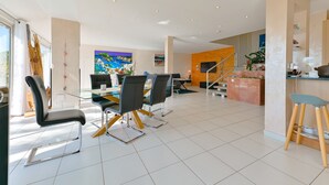 A modern dining area with a glass table, black chairs, and a wooden counter with stools. - Villa 6pers splendid sea view and magnificent landscaped park in the peace with swimming pool (Grosseto-Prugna)