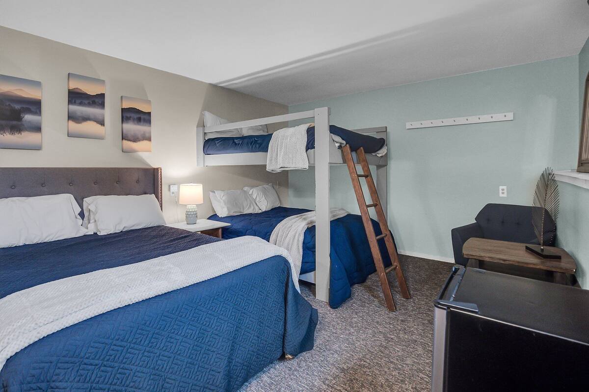 A room with two beds, a desk, a chair, and a ladder.