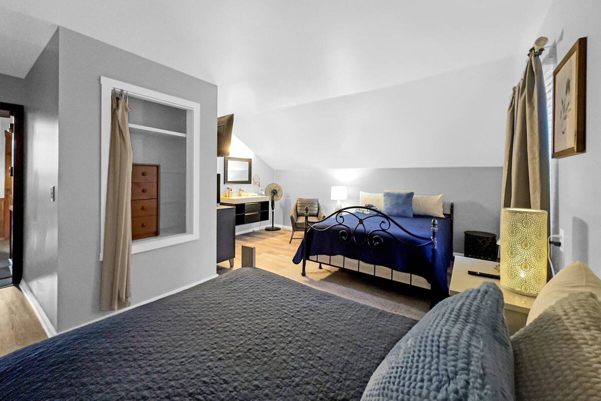A bedroom with a bed, bedside table, lamp, and a window with curtains.