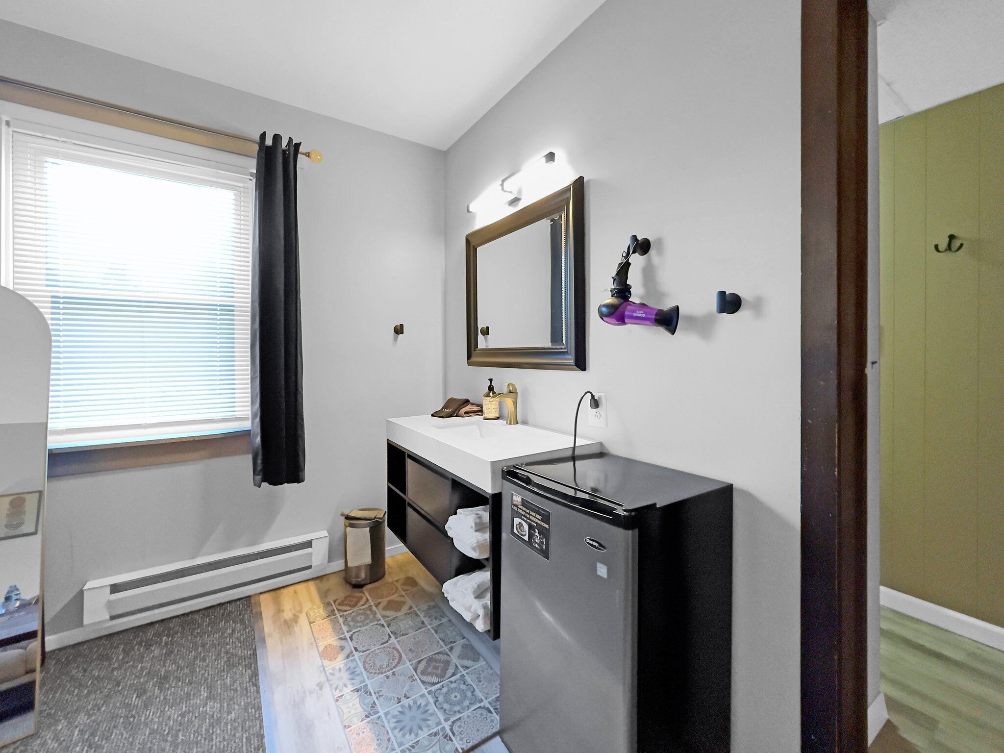 A compact bathroom with a white sink, a mirror, a hairdryer, and a heater.