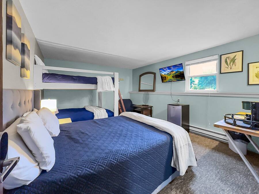 A bedroom with a bunk bed, a desk with a computer, a TV, and framed pictures on the wall.