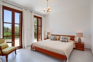 Un dormitorio con una cama grande, dos mesitas de noche, una silla y un balcón con vistas.
