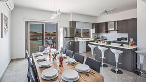 A modern kitchen with a dining area, large windows, and a view of the outdoors. - Villa Jason - Six Bedroom Villa, Sleeps 12 (Paralimni)