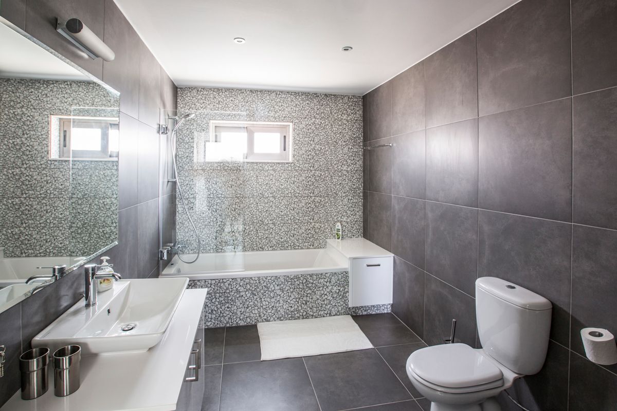 Ein modernes Badezimmer mit Badewanne, Toilette und Waschbecken.