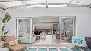 Un intérieur moderne avec une porte vitrée donnant sur un balcon offrant une vue sur l’océan.
