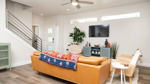 A modern living room with a sofa, a TV, a ceiling fan, and a staircase. - Fun & Good Vibes in Meridian (Meridian)