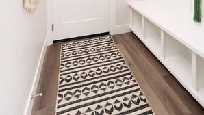 A hallway with a patterned rug, a white door, and a green plant hanging on hooks. - Fun & Good Vibes in Meridian (Meridian)