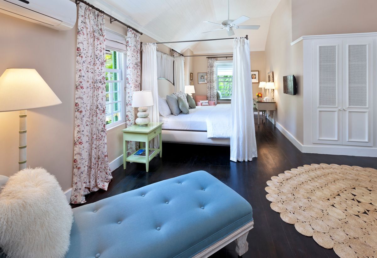 Une chambre à coucher avec un lit, des tables de chevet, un ventilateur de plafond et une grande fenêtre avec des rideaux.