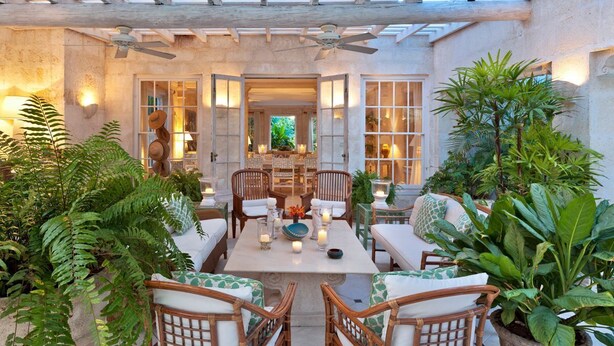 An outdoor patio with wicker furniture, a dining table with candles, and lush greenery. - Leamington House - Five Bedroom Villa, Sleeps 10 (Little Battaleys)