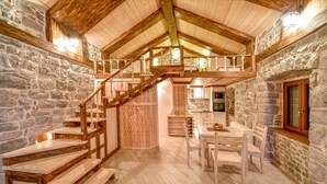 A rustic interior with a stone wall, wooden staircase, and a dining area with a table and chairs. - Villa Kotop - Three Bedroom Villa, Sleeps 6 (Dub, Kotor)