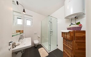 A modern bathroom with a glass shower enclosure, a white sink, and a wooden vanity.