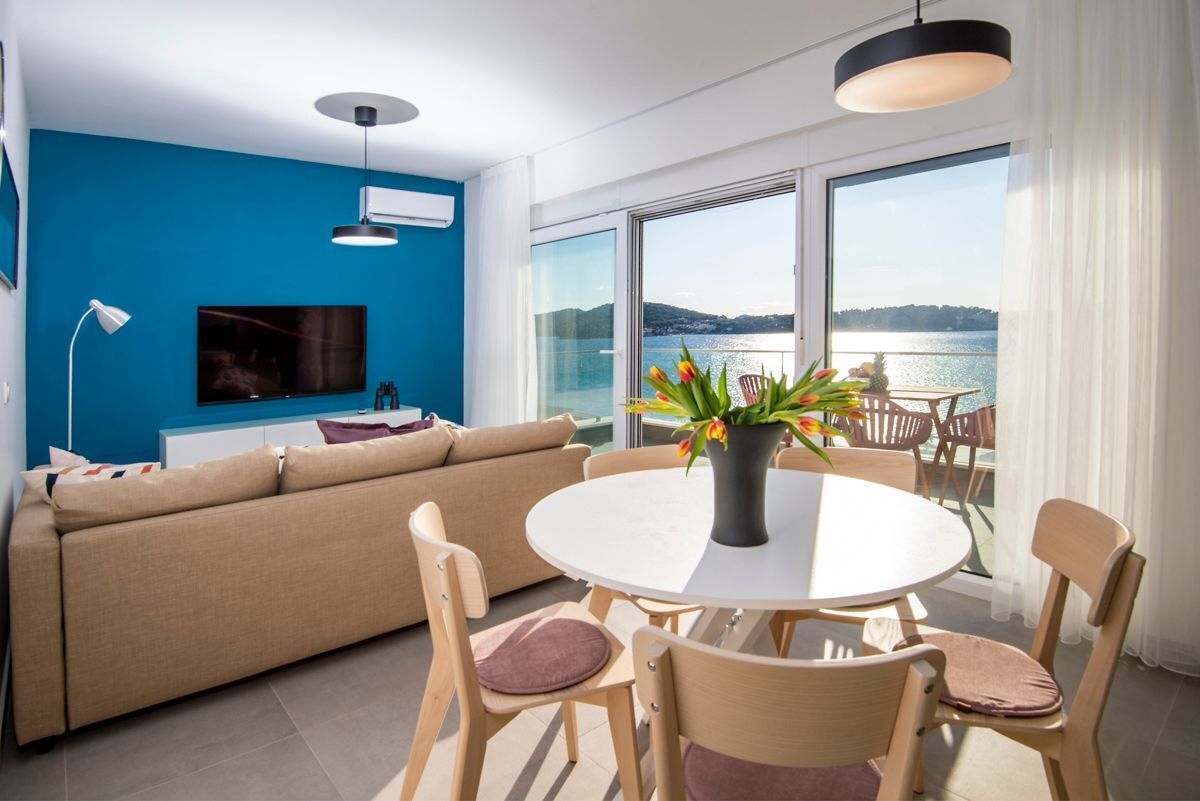 Una sala de estar moderna con sofá, televisor y comedor con sillas y mesa.
