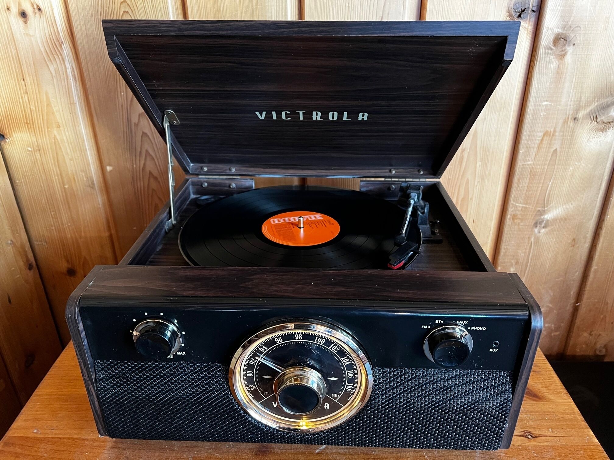 Un tocadiscos Victrola con cubierta de madera y un disco de vinilo adentro.
