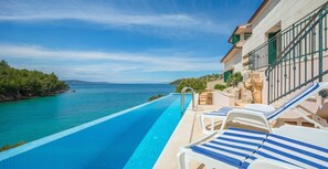 Un espace aménagé au bord de la piscine, avec des chaises longues et une vue sur la mer.