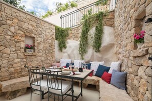 Un espace extérieur aménagé avec des murs en pierre, comprenant une table, des chaises et un banc.