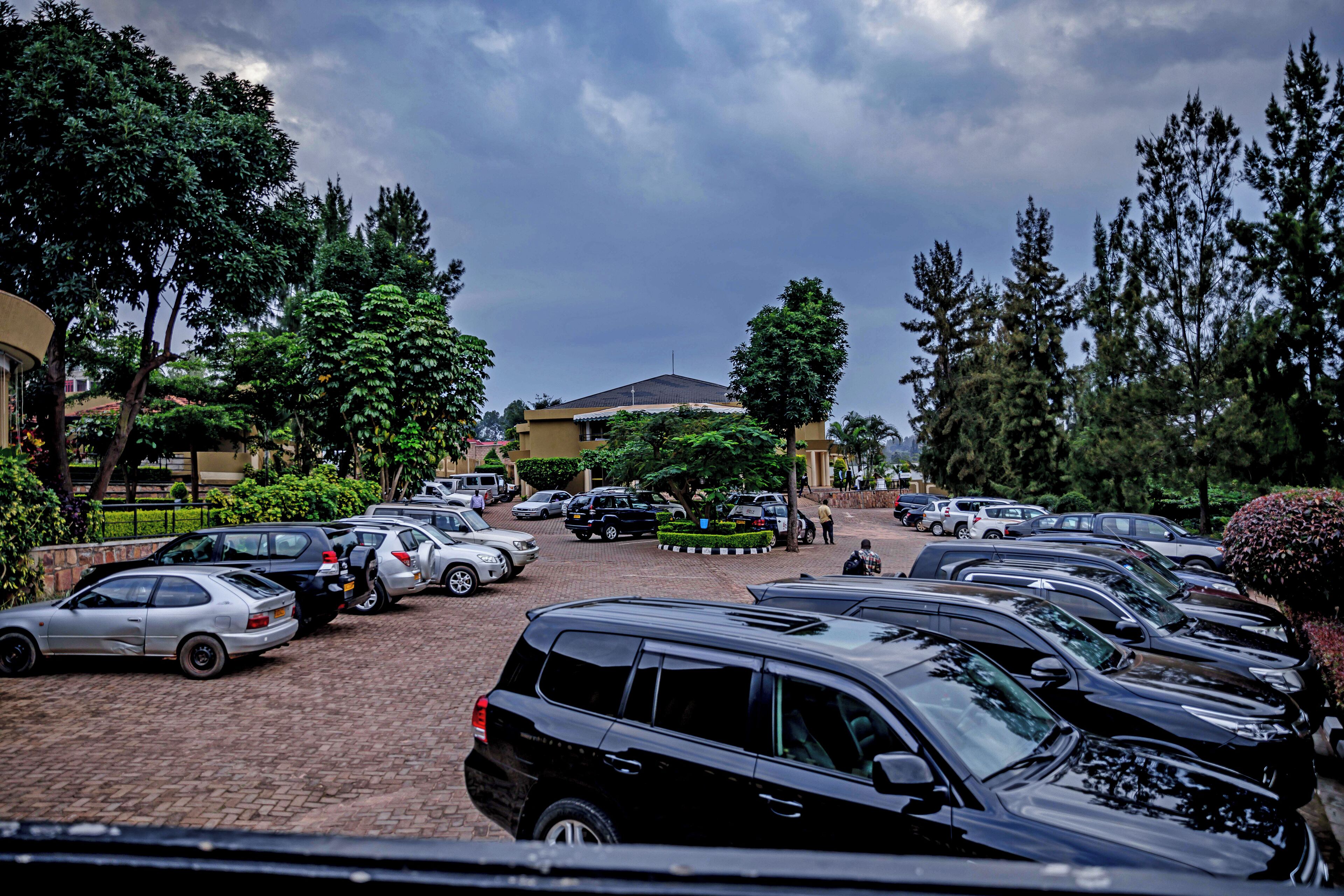 A parking lot with multiple cars, trees, and a building in the background.