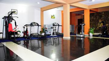 A gym with exercise equipment, a polished floor, and orange walls.