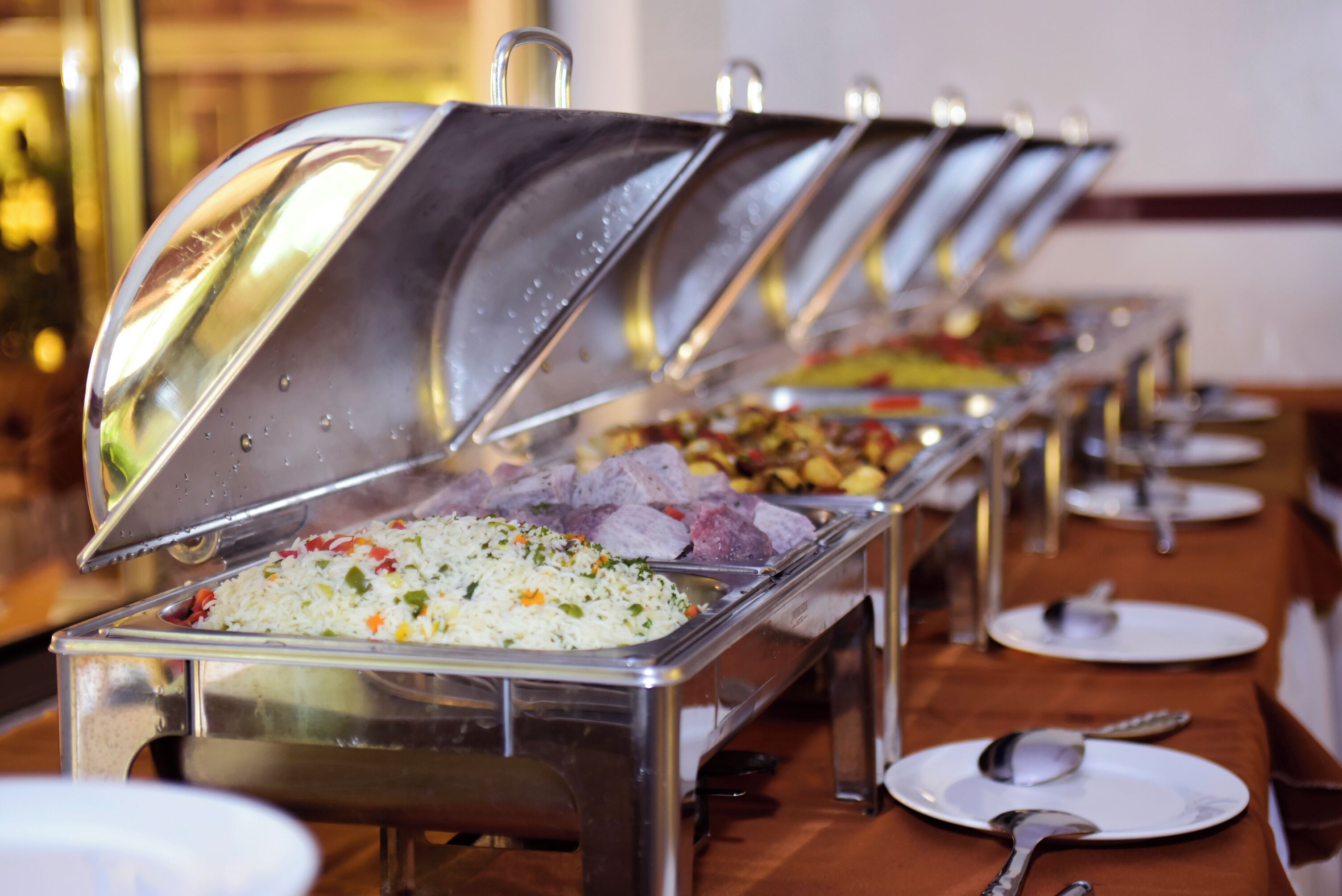 A buffet setup with multiple food stations, including rice and various dishes.