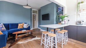 Uma sala de estar moderna com um sofá azul, uma mesa de centro e um espaço de bar com banquetas.