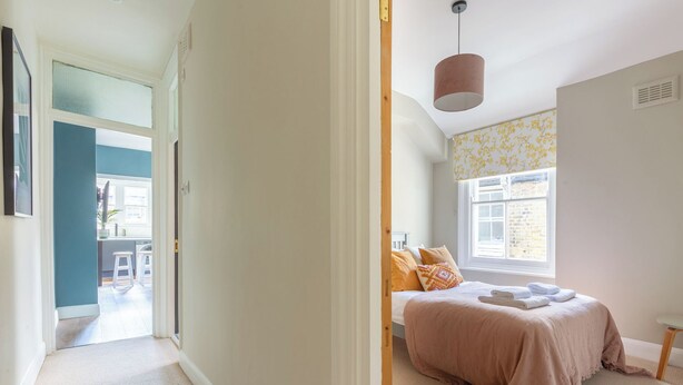 Um quarto com uma cama, uma janela com vista e uma porta que dá para outro espaço.