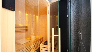A sauna with wooden benches, a glass door, and a shower area.