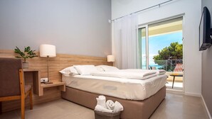 A modern hotel room with a bed, a desk, a chair, a TV, and a balcony with a view.