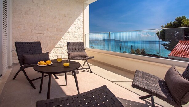 A balcony with a view of a body of water, furnished with two chairs and a table.