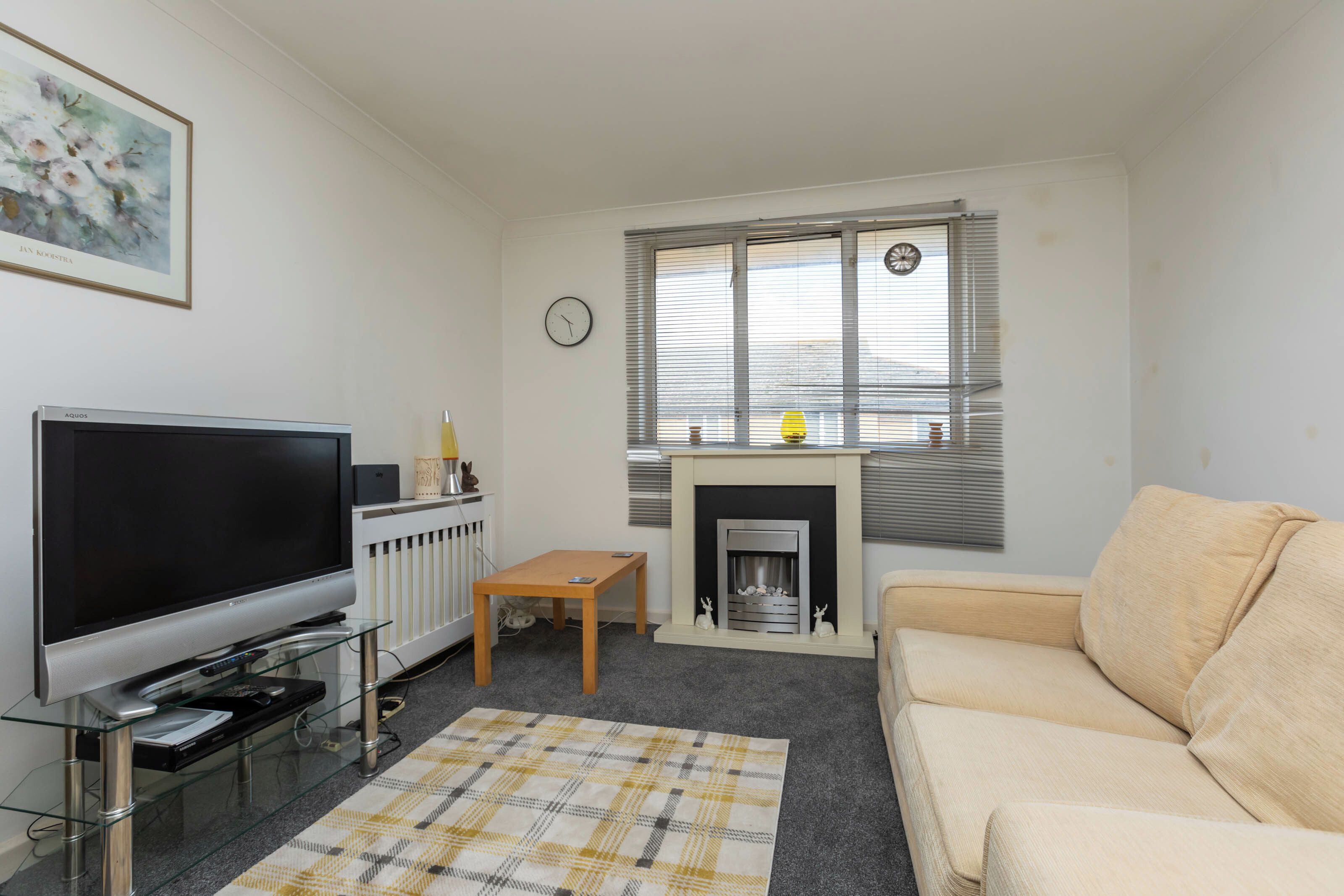 A living room with a television, a fireplace, a sofa, and a painting on the wall.