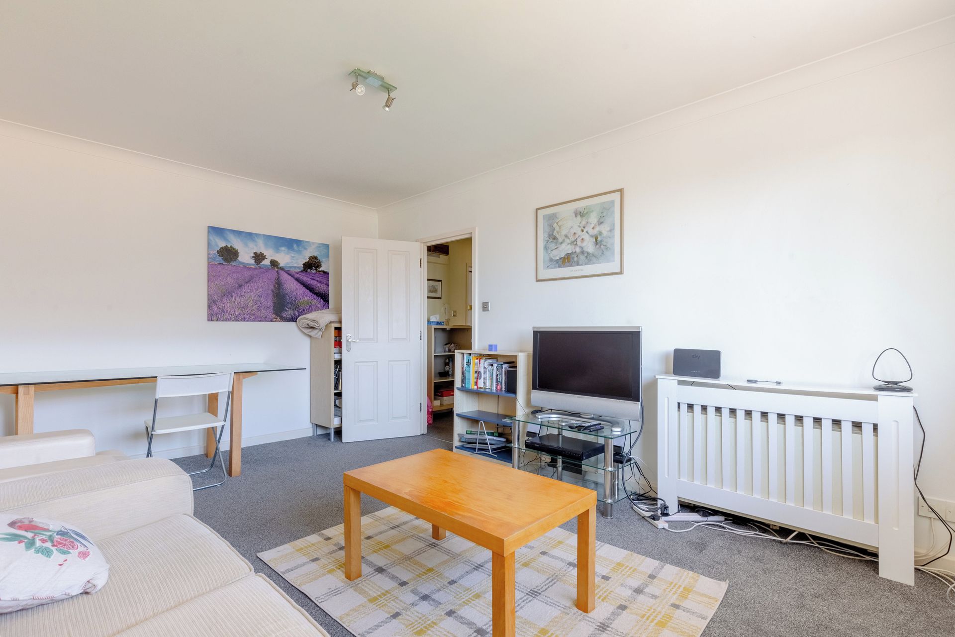A living room with a sofa, a wooden coffee table, a TV, and a radiator.